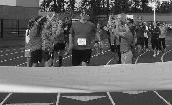 Photo courtesy of Vanessa Anderson
Linfield alum Tony Carpenter (center) gets cheered on by friends as he crosses the finish line of his marathon. The marathon took place Nov. 4 at the Tigard High School track. 