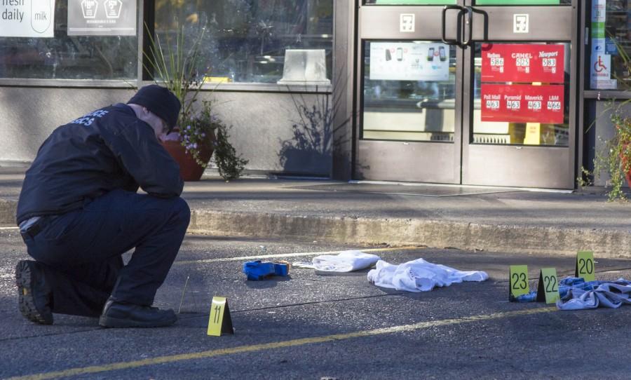 A state forensic police officer examines the crime scene at the 7-Eleven across the street from Linfields campus on Nov. 16.