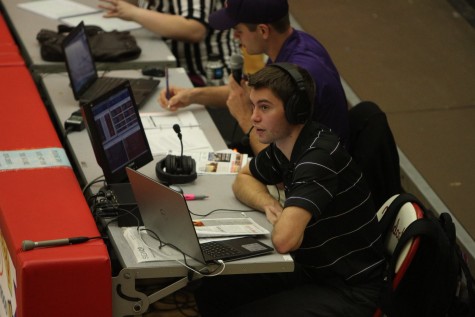 Nelson looks on as he provides comments and play-by-play updates to listen- ers during a basketball game.