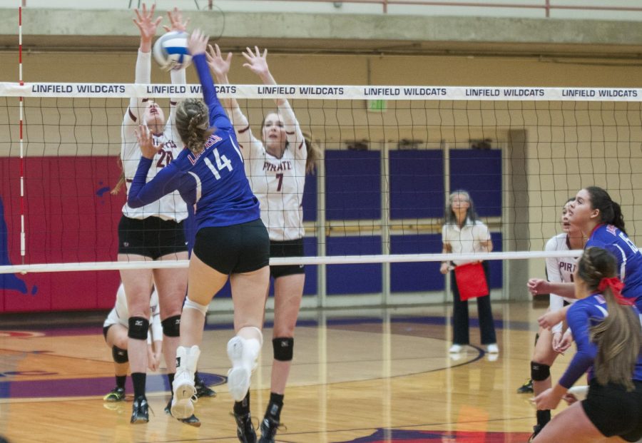 Regan Dean (Linfield 14) moves to spike the ball past Madison Douglas (Whitworth 7) and Lauren Budde (Whitworth 20).
