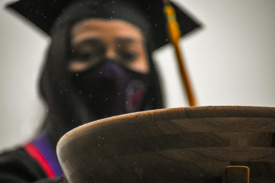 A graduating student drops her acorn back in the bowl. 